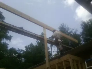 Carpenter setting a ridge beam over a new addition frame — Ice Dam Removal by Roofing Brothers in Savonburg