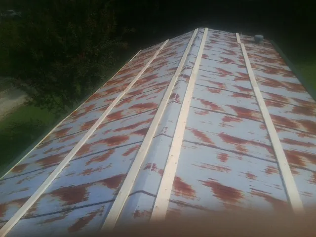 Rusted metal roof panels with new wood purlins before replacement — Storm Damage Roof Repair in Savonburg by Roofing Brothers