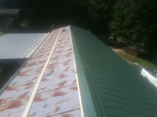 Old rusted panels beside newly installed green metal roofing — Wind Damage Roof Repair by Roofing Brothers in Savonburg