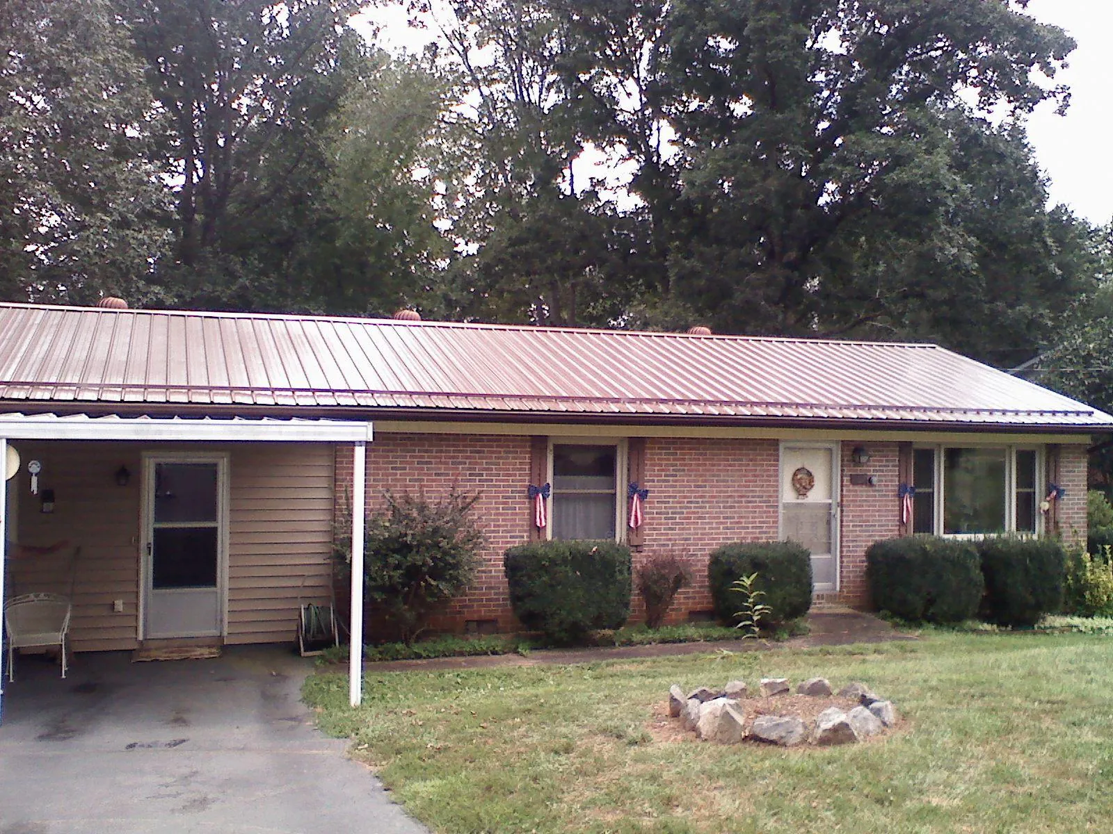 Bronze metal roof and carport on a brick ranch home — Roof Repair work by our crew in Savonburg