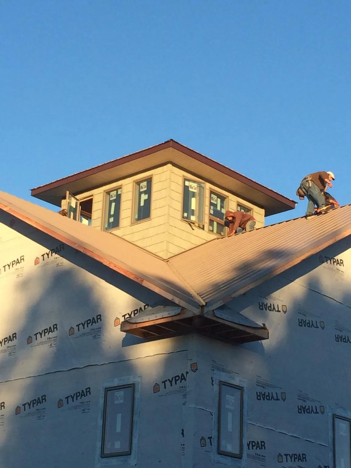 Roofers working around a rooftop cupola on a new metal roof at sunset — Roof Waterproofing in Savonburg by Roofing Brothers